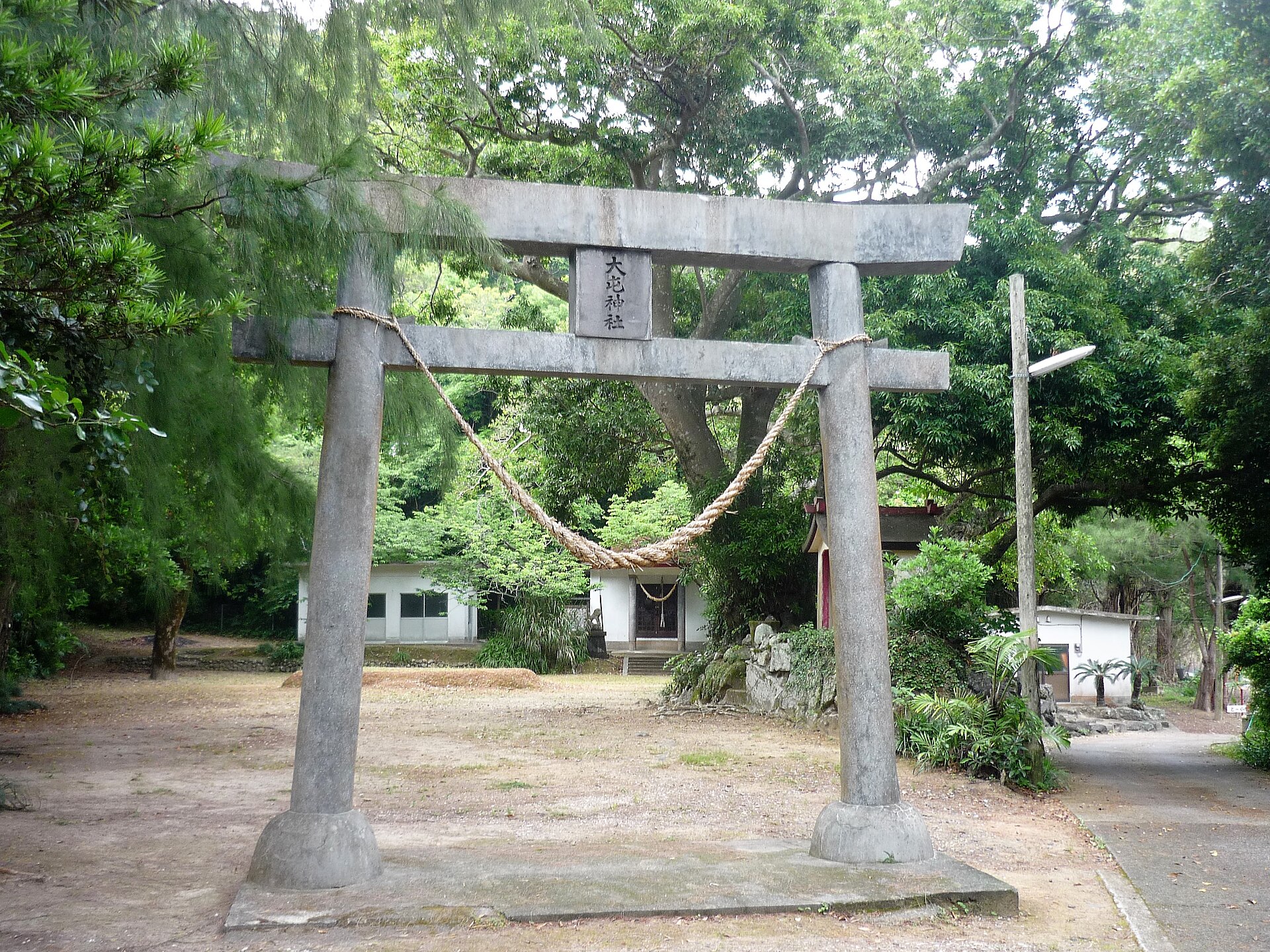 大屯神社(瀬戸内町諸鈍)の石の鳥居を正面から。額に社号があり、注連縄の奥に社殿と境内が写る