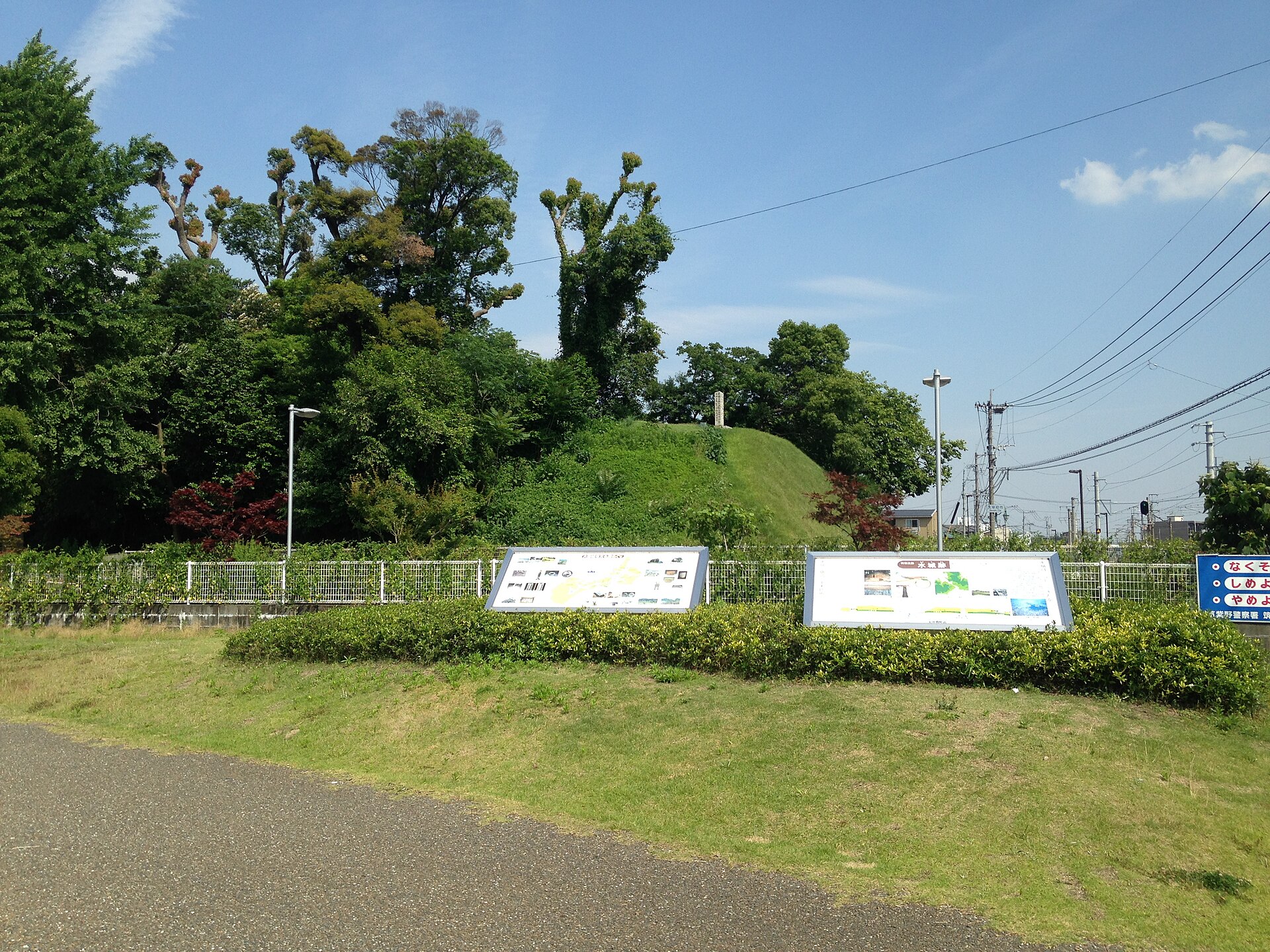 水城跡の土塁を、ふるさと水城跡公園から。芝に覆われた土塁と手前の案内板