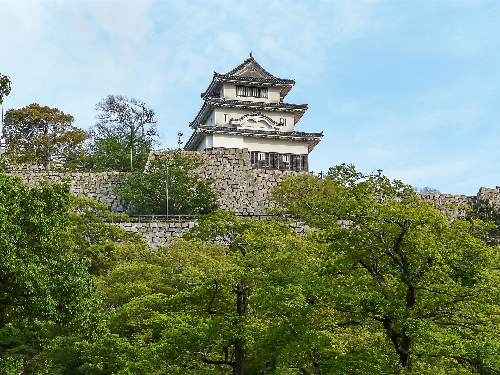 丸亀城の天守を大手二の門付近から見上げた北面。天守の下に積まれた石垣と手前の木々